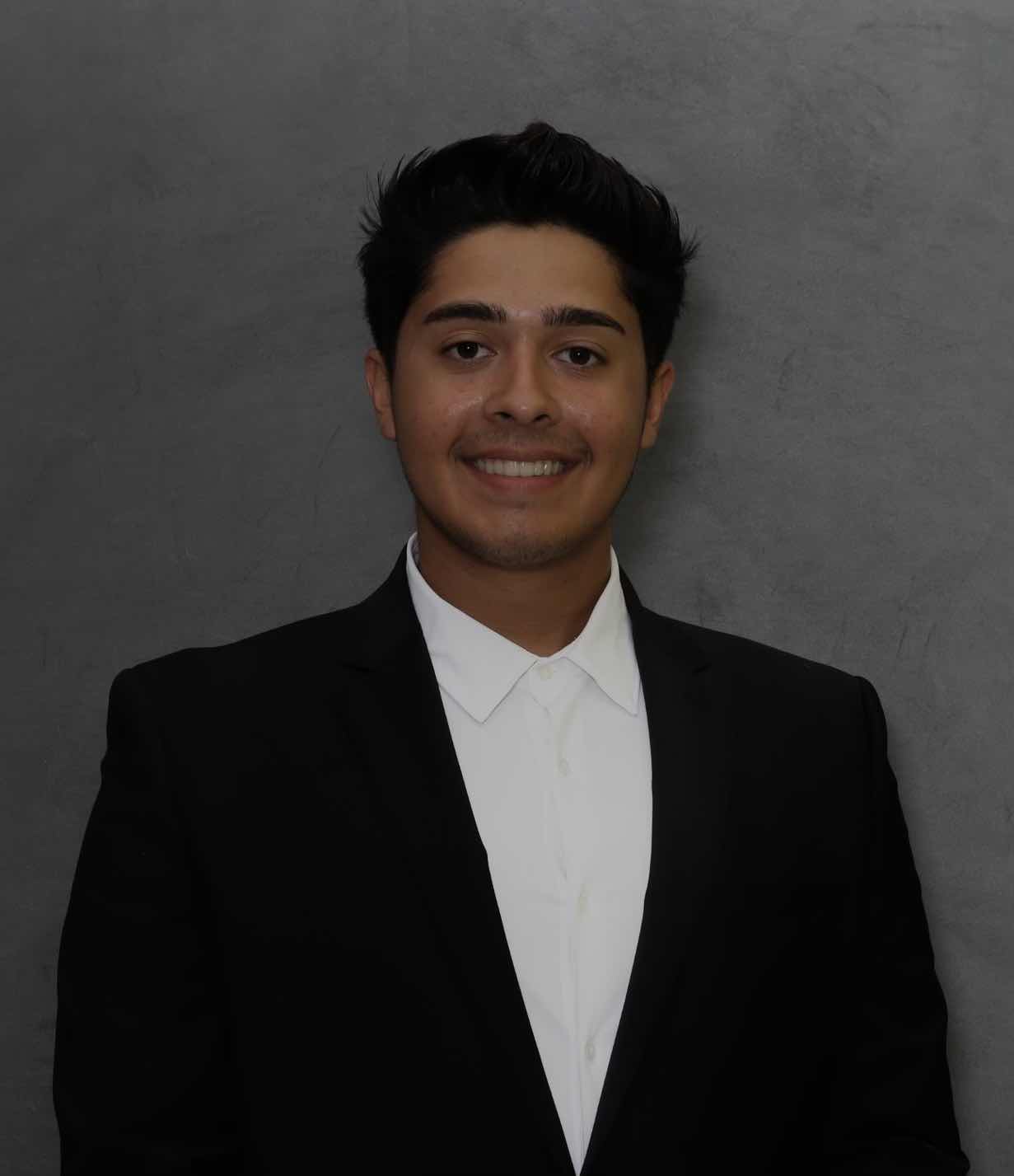 A young man in a suit and tie smiling, radiating confidence and professionalism.